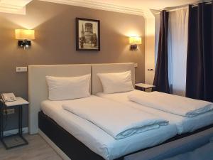 Schlafzimmer mit einem Bett mit weißer Bettwäsche und Kissen in der Unterkunft Rheinmetropole Hotel in Düsseldorf
