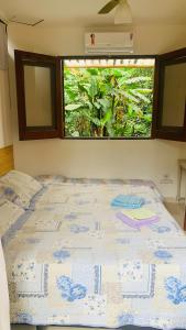 a bed in a room with a large window at Suites surf house itamambuca in Ubatuba