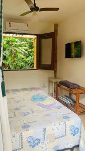 a bedroom with a bed with a ceiling fan and a window at Suites surf house itamambuca in Ubatuba