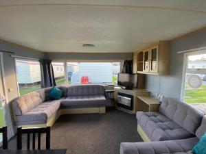 a living room with couches and a tv in a caravan at Seaview 190 - Ingoldmells - Close to beach and Fantasy Island in Ingoldmells