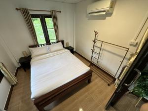 a bedroom with a bed with white sheets and a window at Good View House - Koh Yao Noi in Ko Yao Noi