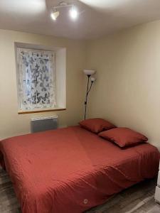Un dormitorio con una cama con sábanas rojas y una lámpara. en Le hameau du Maissubert, 