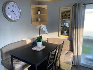a dining room with a table and a clock on the wall at Seaview 190 - Ingoldmells - Close to beach and Fantasy Island in Ingoldmells