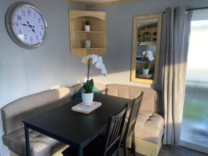 a dining room with a table and a clock on the wall at Seaview 190 - Ingoldmells - pet friendly, WiFi, bed linen - Close to beach and Fantasy Island - Meadow Lakes Caravan & Lodge Hire in Ingoldmells