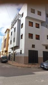 ein weißes Gebäude mit davor geparkt in der Unterkunft Appartement familial in Mohammedia