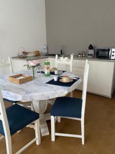 una cocina con una mesa blanca con sillas azules y una mesa en B&B Le Rose, en Villafranca Padovana