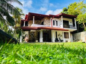 une maison avec une pelouse verte devant elle dans l'établissement Iconic Villa, à Ahangama