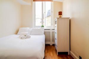 um pequeno quarto com uma cama branca e uma janela em Spacious 4-Bed in St.John's Wood em Londres