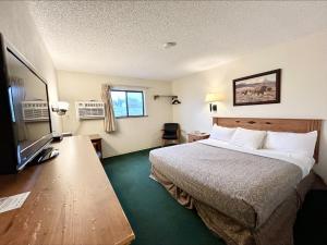 een hotelkamer met een bed en een flatscreen-tv bij Homestead Inn in Wolf Point