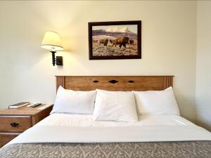 a bedroom with a bed and a picture of cows at Homestead Inn in Wolf Point