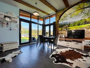 a dining room with a table and chairs and a tv at Casuta de sub stanca Apuseni,hot tub inclus in Bîrdeşti