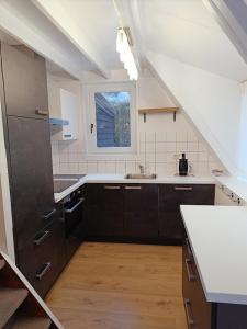 een keuken met zwarte kasten en een raam bij Molière in Rekem