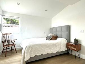 um quarto com uma cama, uma cadeira e uma janela em The Village House em Garnsey