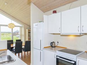 una cocina con armarios blancos y una mesa con sillas. en 10 person holiday home in Brovst, en Brovst