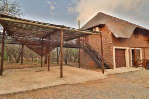 a brick building with a thatched roof and a staircase at Leopard Chalet in Marloth Park