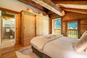 - une chambre avec un grand lit dans une pièce dotée de murs en bois dans l'établissement Chalet le 4 - 13 personnes, au Grand-Bornand