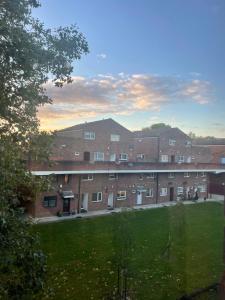 a large brick building with a grass field in front at Modern big 2 bedroom in Northolt with terrace parking in Northolt