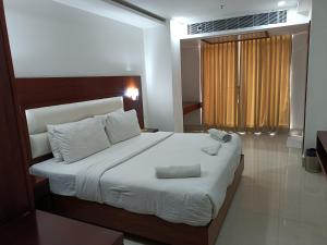 a bedroom with a large bed with white sheets at Hotel Autumn Crocus in Guwahati +60 photos