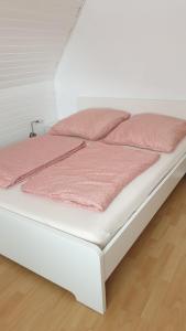 ein weißes Bett mit rosa Kissen darüber in der Unterkunft Private Unterkunft, ruhige Lage in Nordhorn-Klausheide in Nordhorn