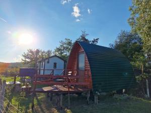 a small cabin with a deck and a house at Căsuța Sara- the story of nature in Plopi