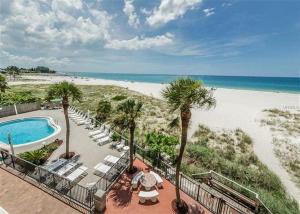 a resort with a pool and a beach with palm trees at Beachfront Madeira Norte in St. Pete Beach