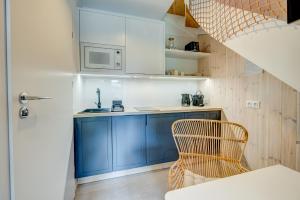 uma cozinha com armários azuis e uma cadeira num quarto em HUS - caloroczne komfortowe szeregi blisko plazy em Pobierowo