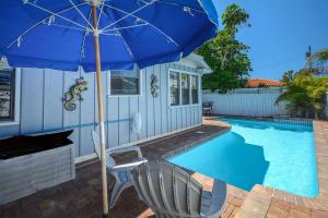 a blue umbrella and a chair next to a swimming pool at Coconut Beach House in Clearwater Beach