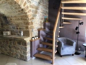 a winding staircase in a room with a stone wall at Gîte La Laiterie - La Planhe in Bozouls