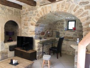 een woonkamer met een tafel en een televisie in een stenen muur bij Gîte La Laiterie - La Planhe in Bozouls