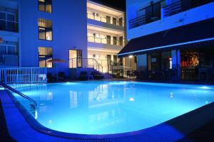 a large swimming pool in front of a building at night at Poseidon Deluxe Apartments in Kos