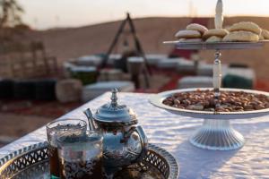 - une table avec une tasse de café et une assiette de biscuits dans l'établissement SAHARA WAVES CAMP, à Merzouga