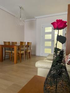 un soggiorno con un tavolo e un vaso con una rosa di Apartamentos Plaza del Arco a Caravaca de la Cruz