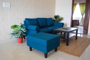 a living room with a blue couch and a table at StayMazing-1,2 & 3 BHK AC Apartments in Hebbal-5mins to Manyata-30mins to Airport in Bangalore