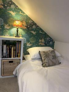 a bedroom with a bed and a book shelf with a lamp at Charming artist’s cottage in East Knoyle