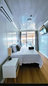ein Schlafzimmer mit einem weißen Bett in einem Zimmer mit Fenstern in der Unterkunft Suites Bocas del Toro in Carenero