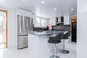 cocina con nevera de acero inoxidable y 2 taburetes en Gorgeous 5 Bedroom House, en Brossard