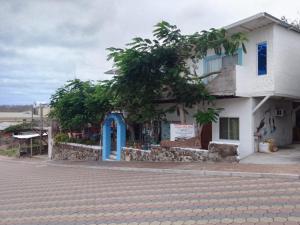 biały budynek z niebieskimi drzwiami na ulicy w obiekcie Hostal Cabañas Don Jorge w mieście Puerto Baquerizo Moreno