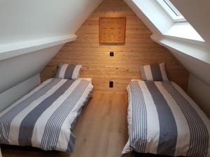 two beds in a attic room with wooden walls at Vakantiehuis Hanna in Zedelgem