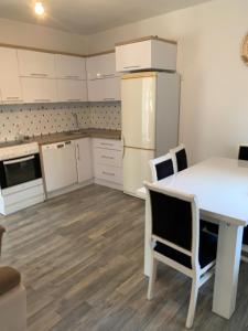 a kitchen with a white table and a white refrigerator at FetiCozyhome in Prishtinë