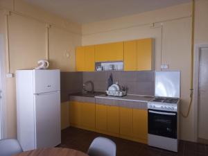 eine Küche mit gelben Schränken und einem weißen Kühlschrank in der Unterkunft Веселый домик in Lazarevo