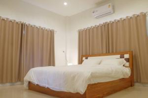 um quarto com uma cama com lençóis brancos e cortinas em วิลล่าสุดชีค ในเชียงราย em Ban Pa Faek