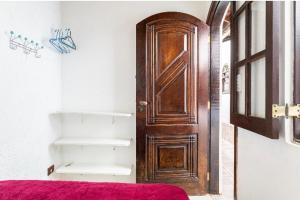 - une chambre avec une porte en bois et un lit rouge dans l'établissement SUITES CONFORTÁVEIS CASAL OU QUATRO PESSOAS, à São Sebastião