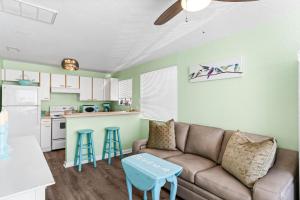 a living room with a couch and a kitchen at Canary Beach Cottage in Clearwater Beach