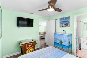 a bedroom with a bed and a flat screen tv at Canary Beach Cottage in Clearwater Beach