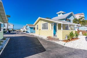 une maison jaune avec une porte bleue dans une rue dans l'établissement Canary Beach Cottage, à Clearwater Beach