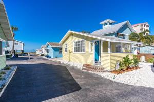 una casa amarilla con una puerta azul en una calle en Canary Beach Cottage, en Clearwater Beach