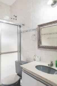 ein Badezimmer mit einem Waschbecken, einem WC und einem Spiegel in der Unterkunft SUITES CONFORTÁVEIS CASAL OU QUATRO PESSOAS in São Sebastião