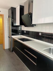 a kitchen with white and black cabinets and a sink at Cómodo apartamento a pie de carretera in Alhendín