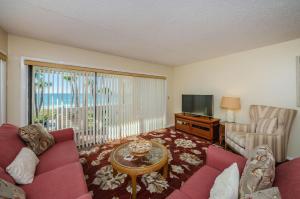 a living room with a couch and a table and a tv at Beachfront Aldea 6 in Clearwater Beach