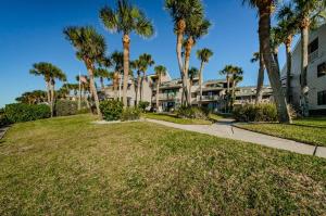 a large apartment building with palm trees and a sidewalk at Beachfront Aldea 6 in Clearwater Beach